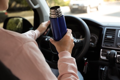 Photo of Woman with thermos driving car, closeup view