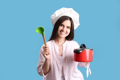 Photo of Happy young woman with cooking pot and ladle on light blue background