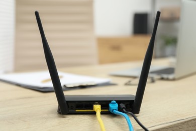 Photo of Modern Wi-Fi router on wooden table indoors
