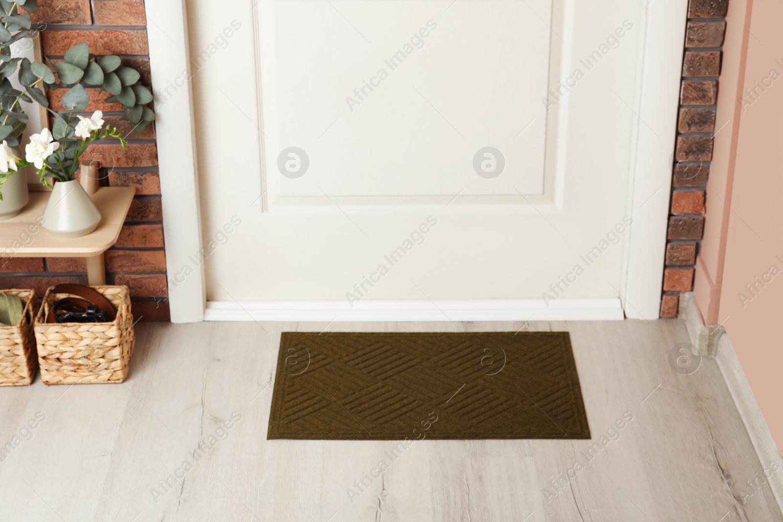 Photo of Dark olive door mat on wooden floor in hall