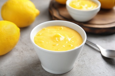 Photo of Delicious lemon curd in bowl on grey table, closeup