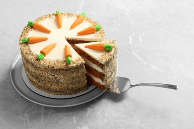 Photo of Sweet carrot cake with delicious cream and server on grey marble table. Space for text