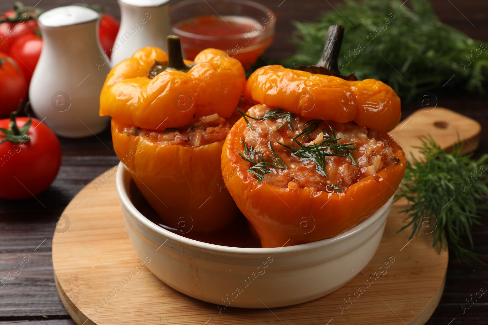 Photo of Tasty stuffed peppers in bowl on wooden table, closeup