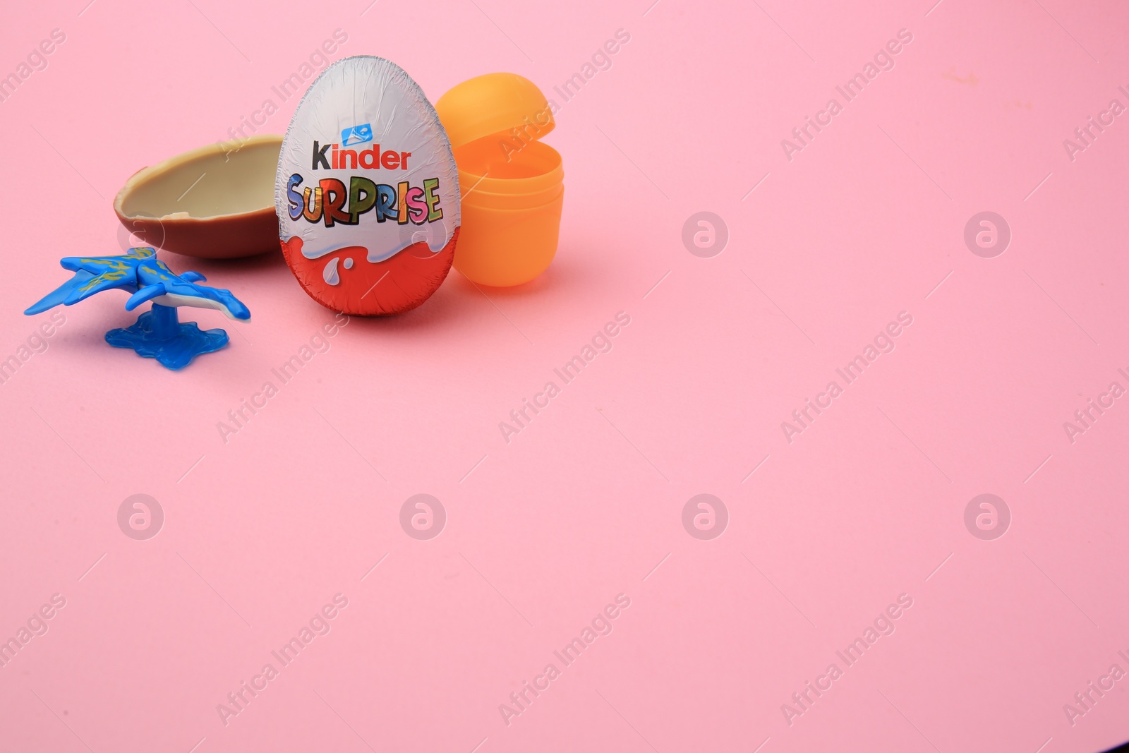 Photo of Sveti Vlas, Bulgaria - June 30, 2023: Kinder Surprise Eggs, open plastic capsule and toy on pink background, space for text