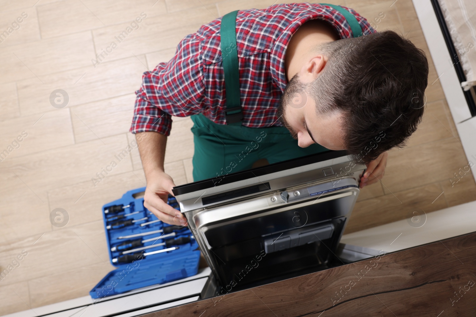 Photo of Serviceman examining dishwasher's door indoors, above view