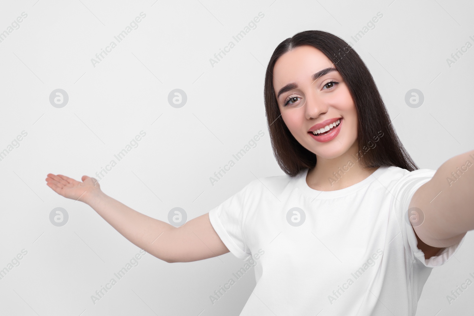 Photo of Smiling young woman taking selfie on white background