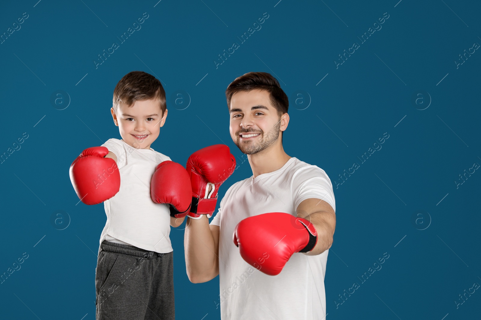 Photo of Dad and his son with boxing gloves on color background