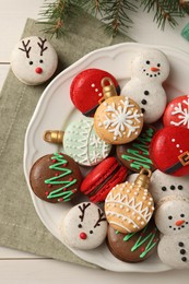 Photo of Beautifully decorated Christmas macarons on white wooden table, flat lay