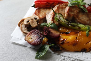 Tasty grilled meat and vegetables on light table, closeup