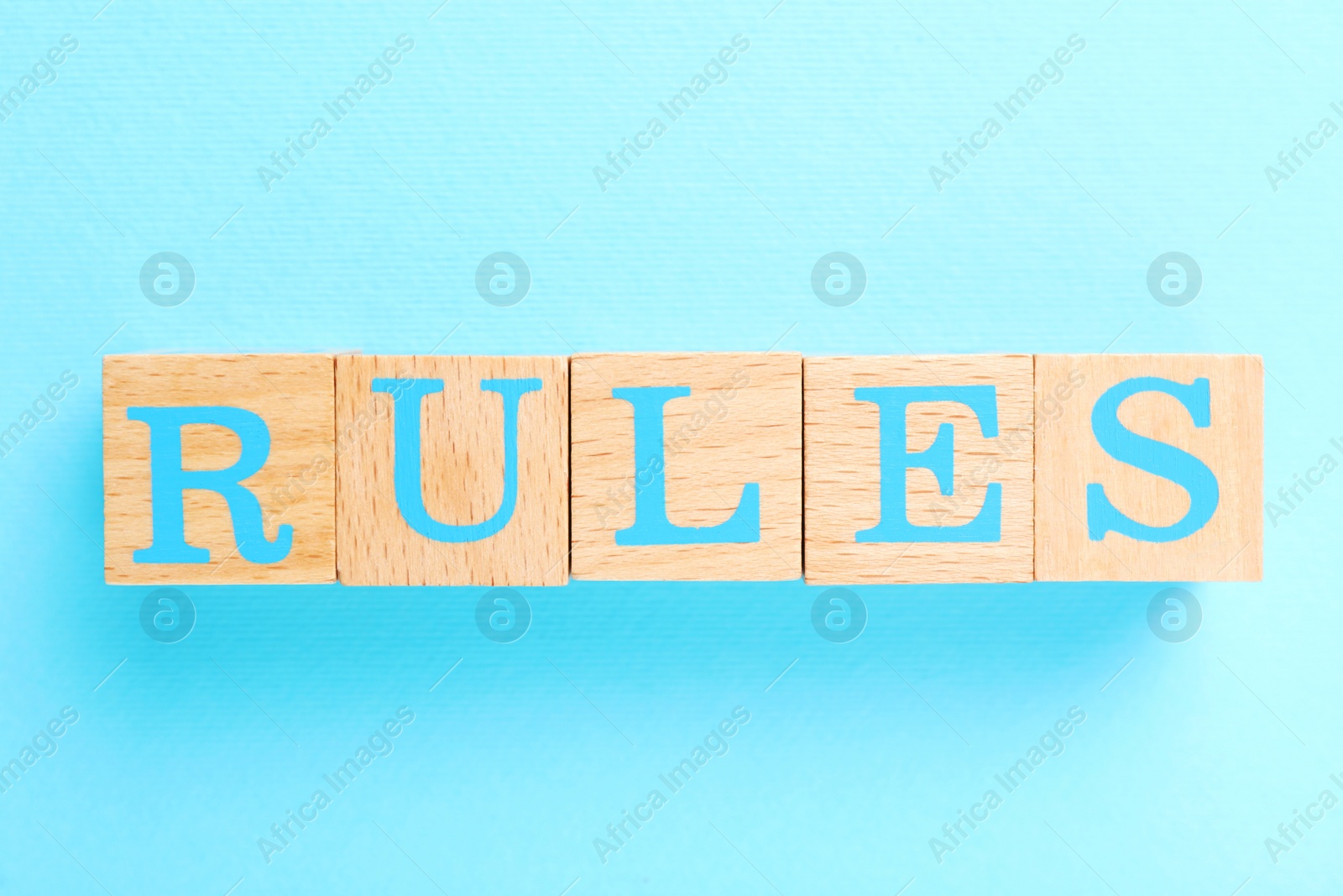 Photo of Word Rules made of wooden cubes with letters on light blue background, flat lay