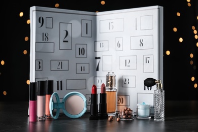 Photo of Christmas advent calendar with perfumes, skin care and decorative cosmetics on table
