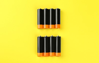 New AA batteries on yellow background, flat lay