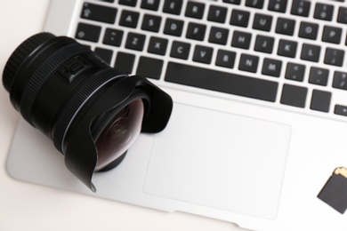 Camera lens on laptop, closeup. Professional photographer's equipment