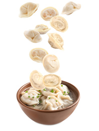 Many tasty dumplings falling into bowl on white background