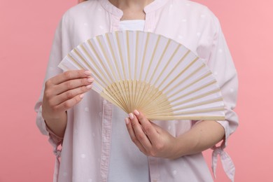 Woman with hand fan on pink background, closeup