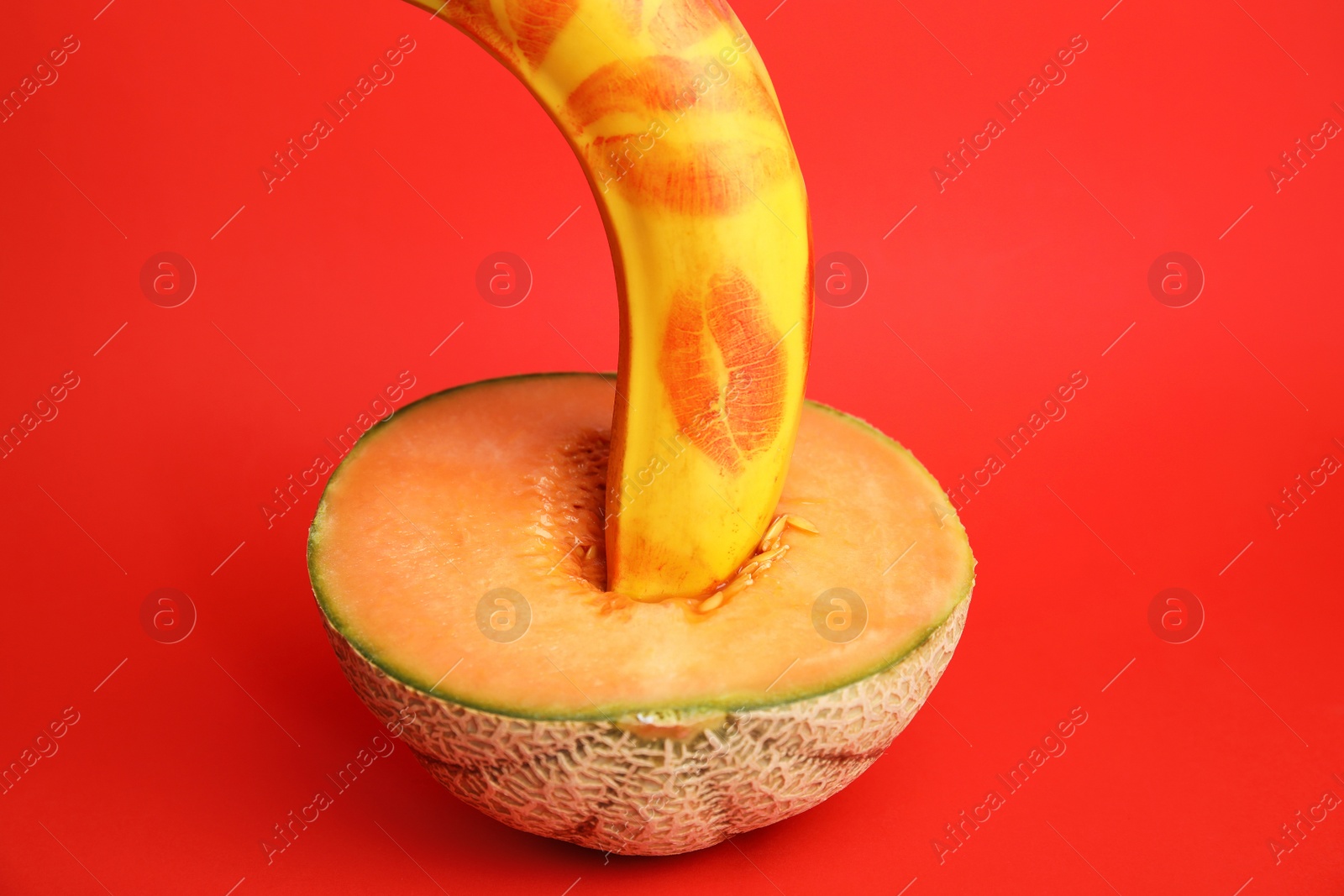Photo of Fresh banana with lipstick marks and melon on red background. Sex concept