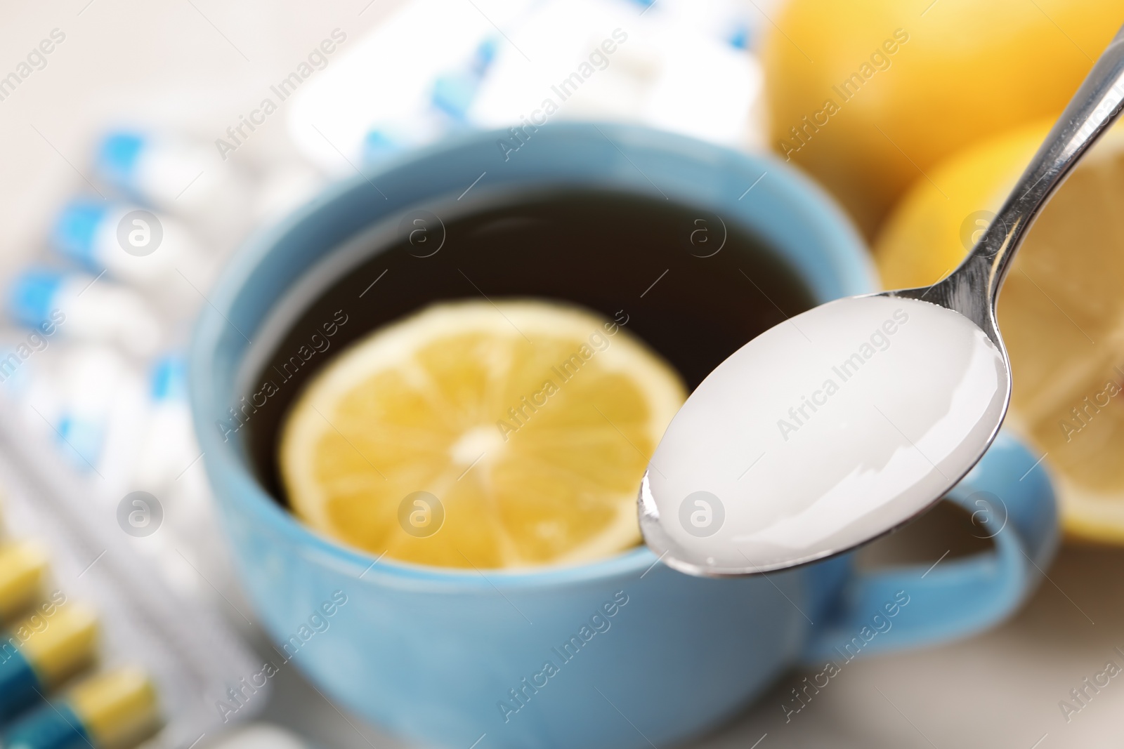 Photo of Spoon with cough syrup on blurred background, closeup