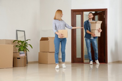 Photo of Couple walking into their new house with moving boxes