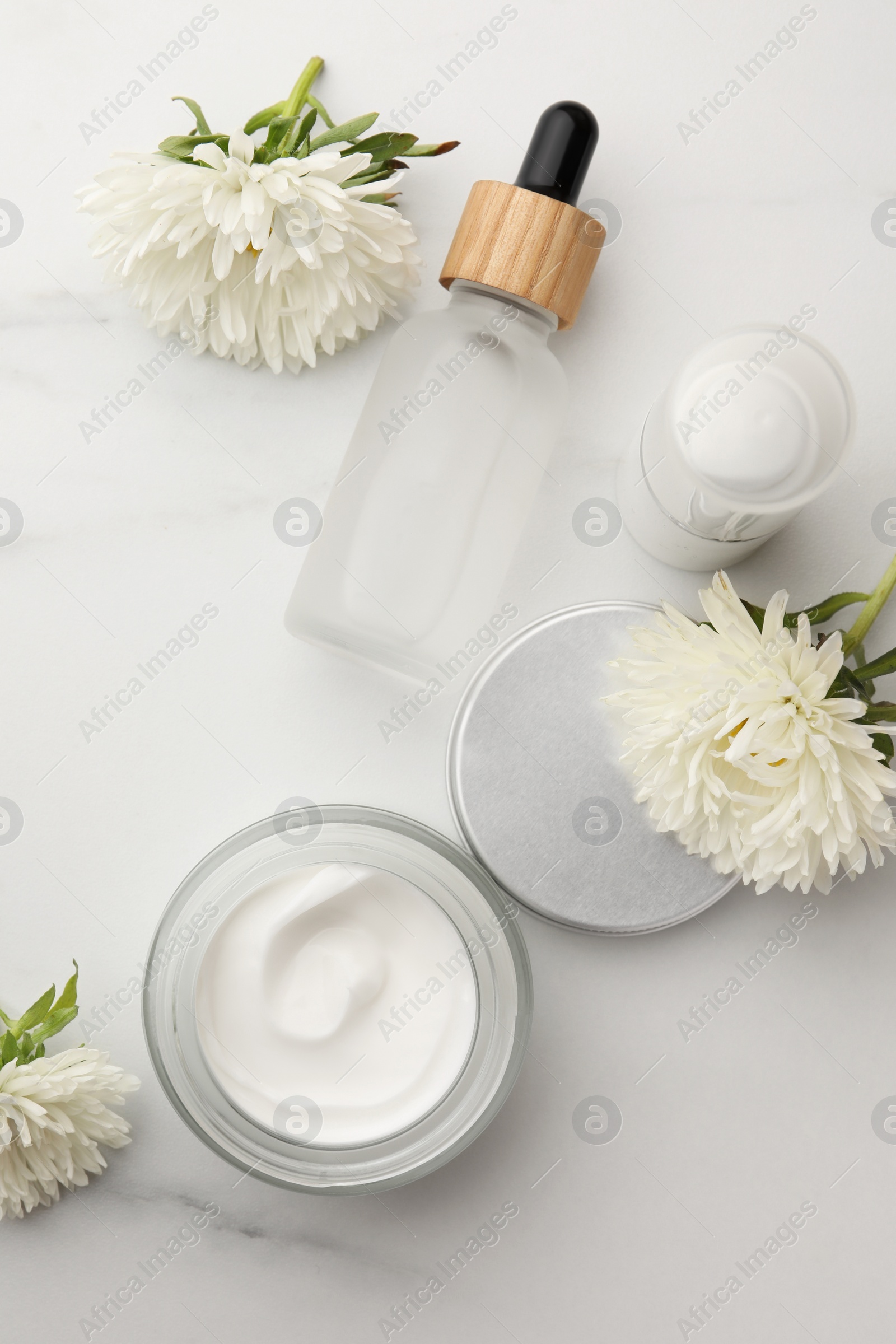 Photo of Glass jar of face cream and other cosmetic products on white marble table, flat lay