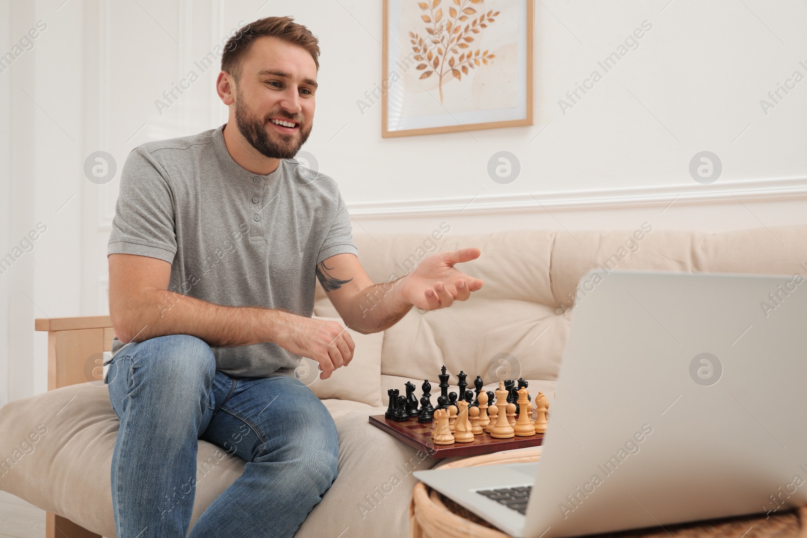 Photo of Young man playing chess with partner through online video chat at home