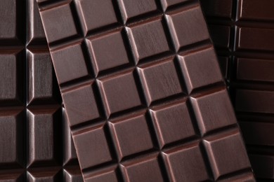 Photo of Many delicious dark chocolate bars as background, top view