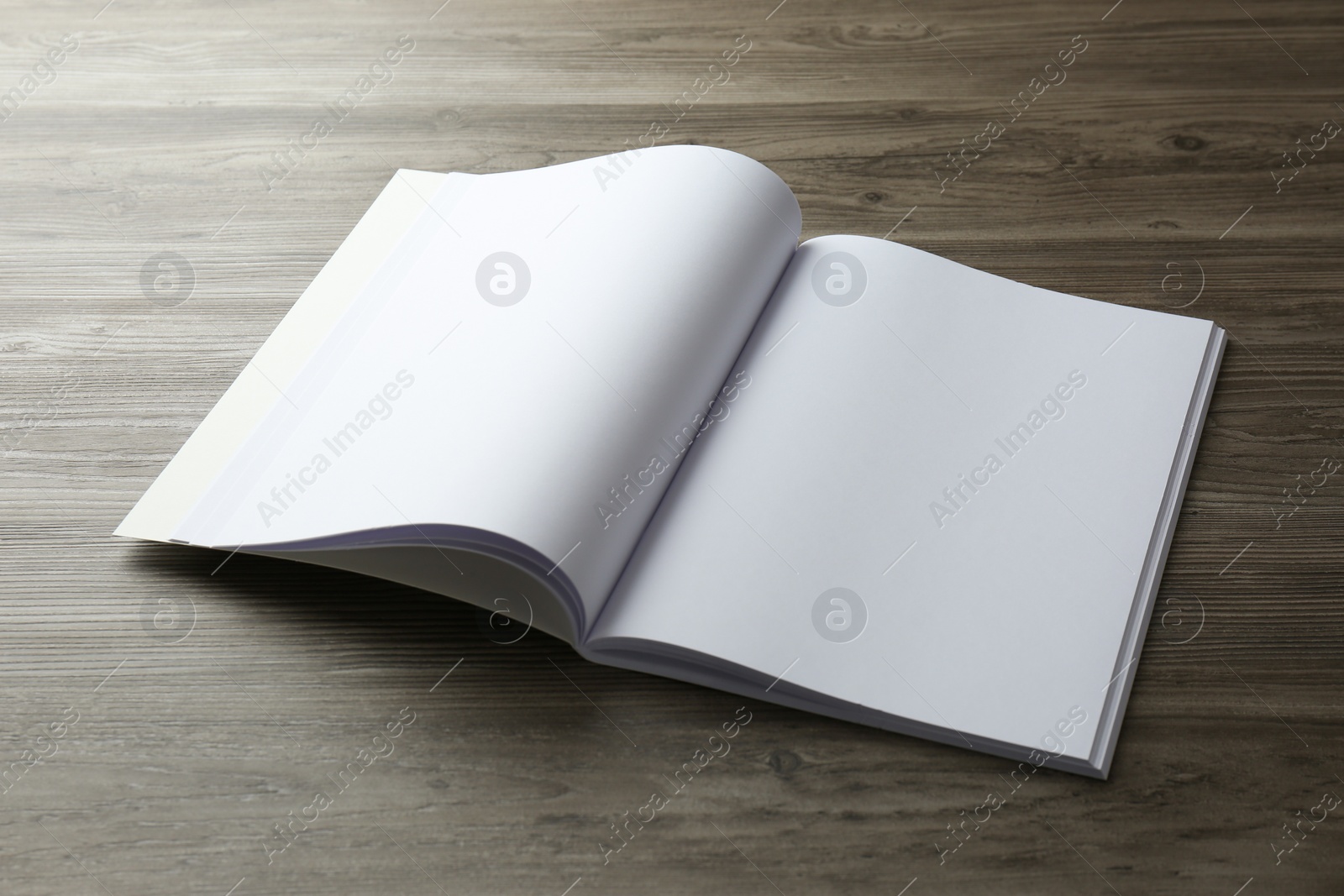 Photo of Open blank paper brochure on wooden table. Mockup for design