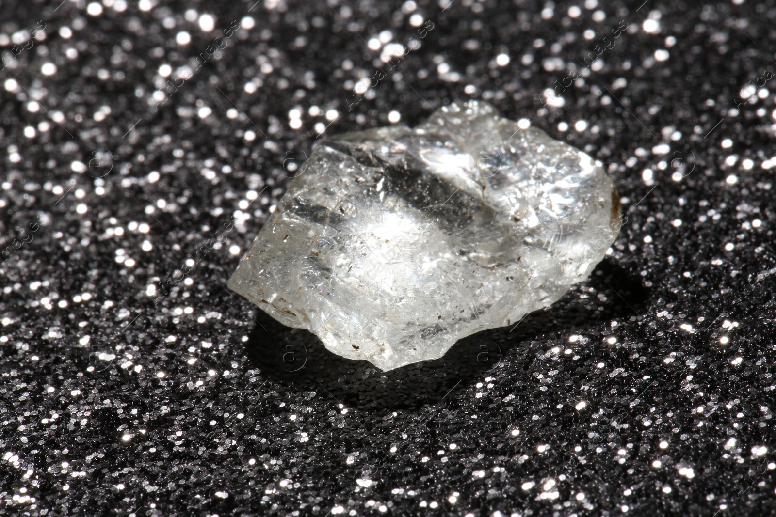 Photo of Beautiful rough diamond on dark shiny background, closeup