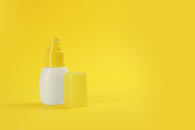Bottle with insect repellent spray on yellow background, space for text