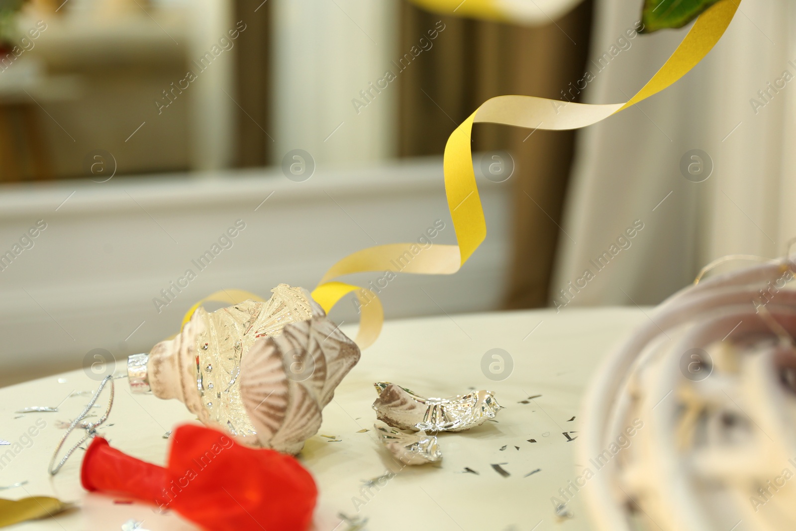 Photo of Broken bauble on white table. Mess after new year party