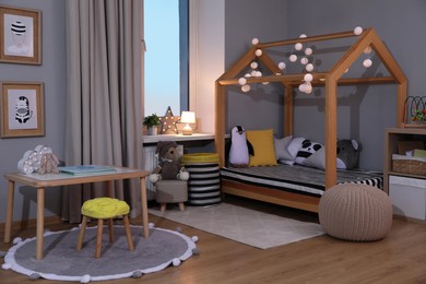 Photo of Stylish child room interior with comfortable house bed and toys