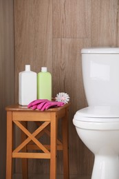 Photo of Cleaning supplies on stool near toilet bowl indoors