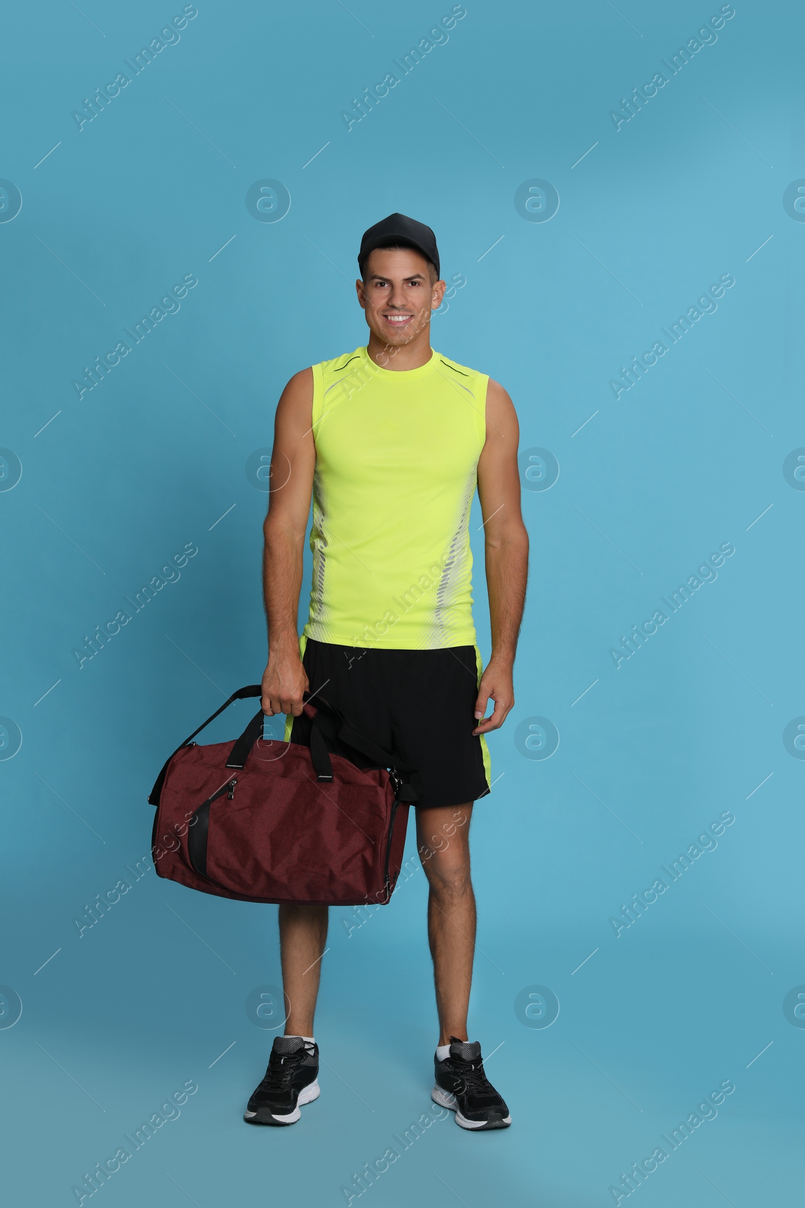 Photo of Handsome man with sports bag on light blue background