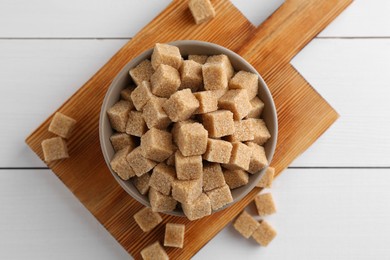 Photo of Brown sugar cubes on white wooden table, flat lay