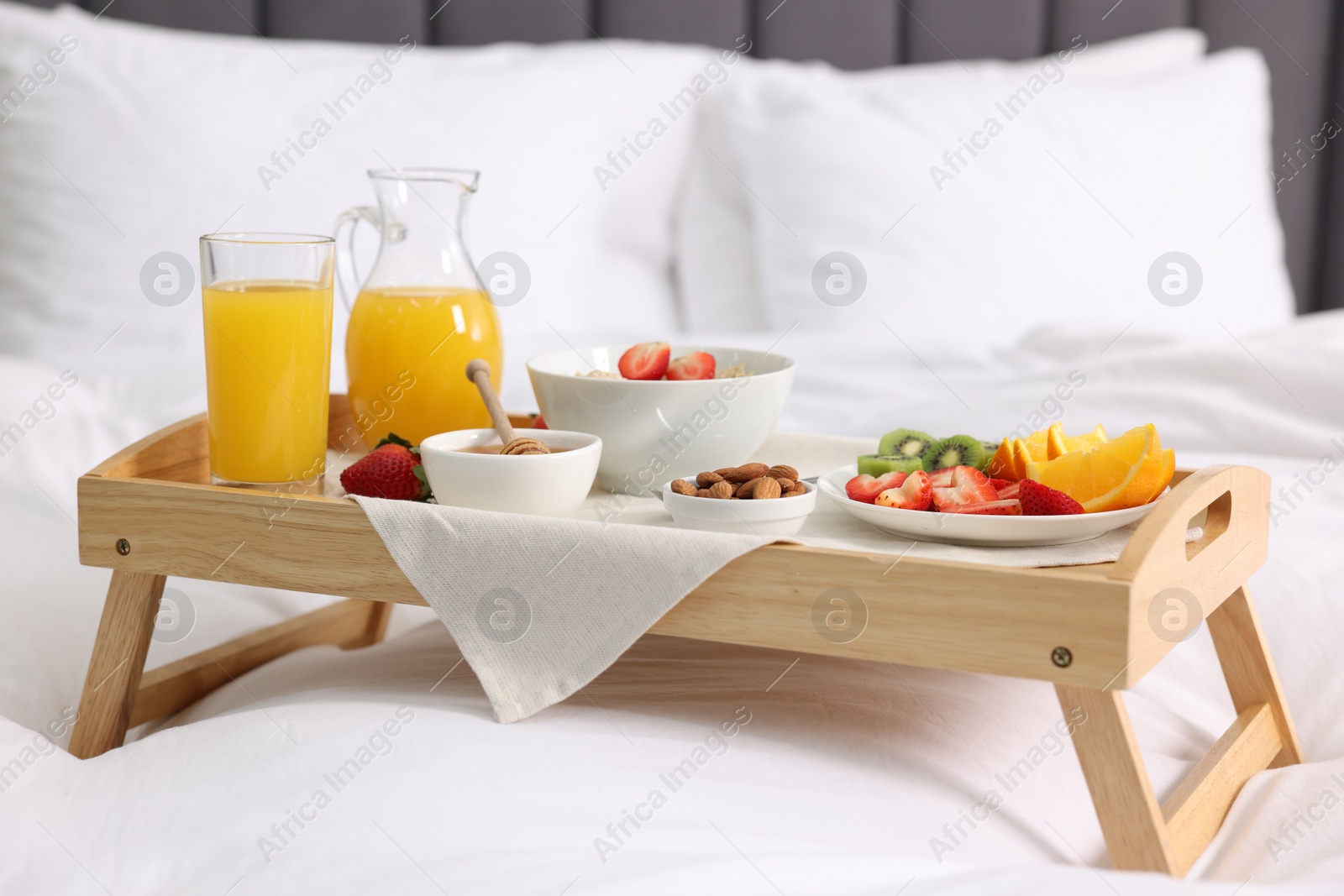 Wooden tray with tasty breakfast on bed at home Photo of Wooden tray with tasty breakfast on bed at home