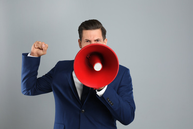 Handsome man with megaphone on grey background