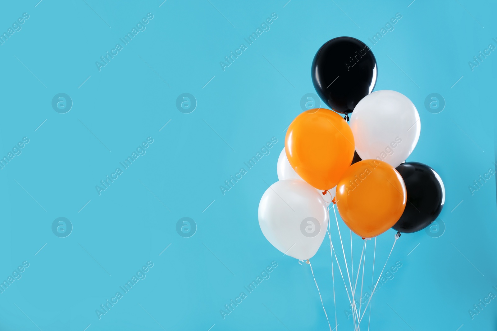 Photo of Colorful balloons on blue background, space for text. Halloween party