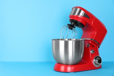 Photo of Modern red stand mixer on turquoise background, space for text