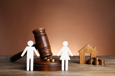 Divorce concept. Gavel, wedding rings and paper cutout of couple on wooden table