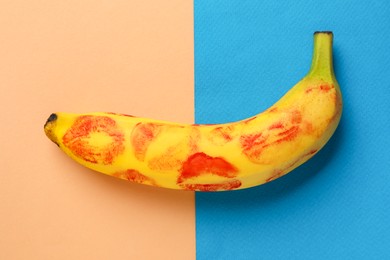 Banana with red lipstick marks on color background, top view. Sex concept