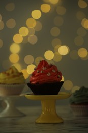 Photo of Delicious cupcake on table against blurred lights