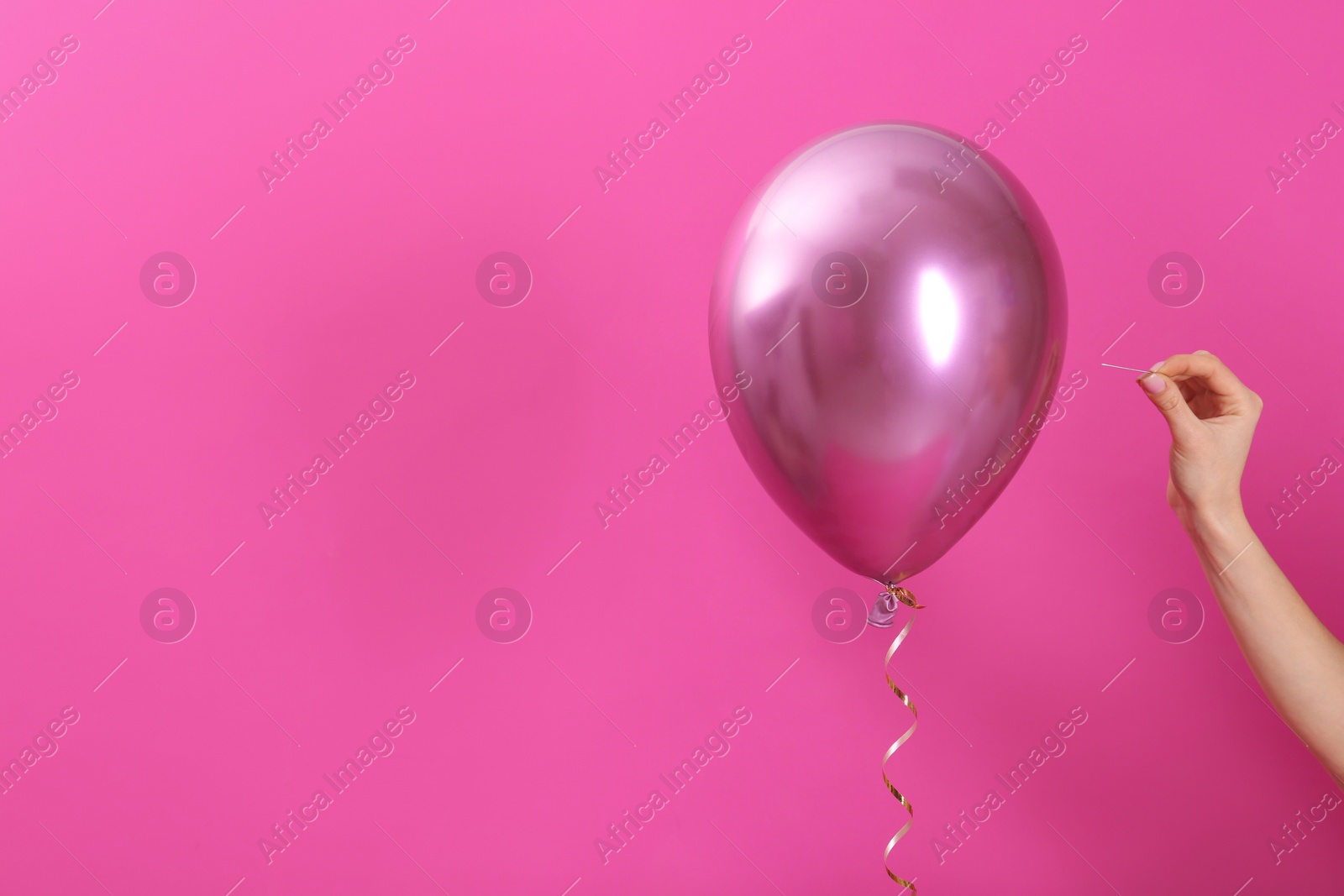 Photo of Woman piercing balloon with needle on color background, closeup. Space for text