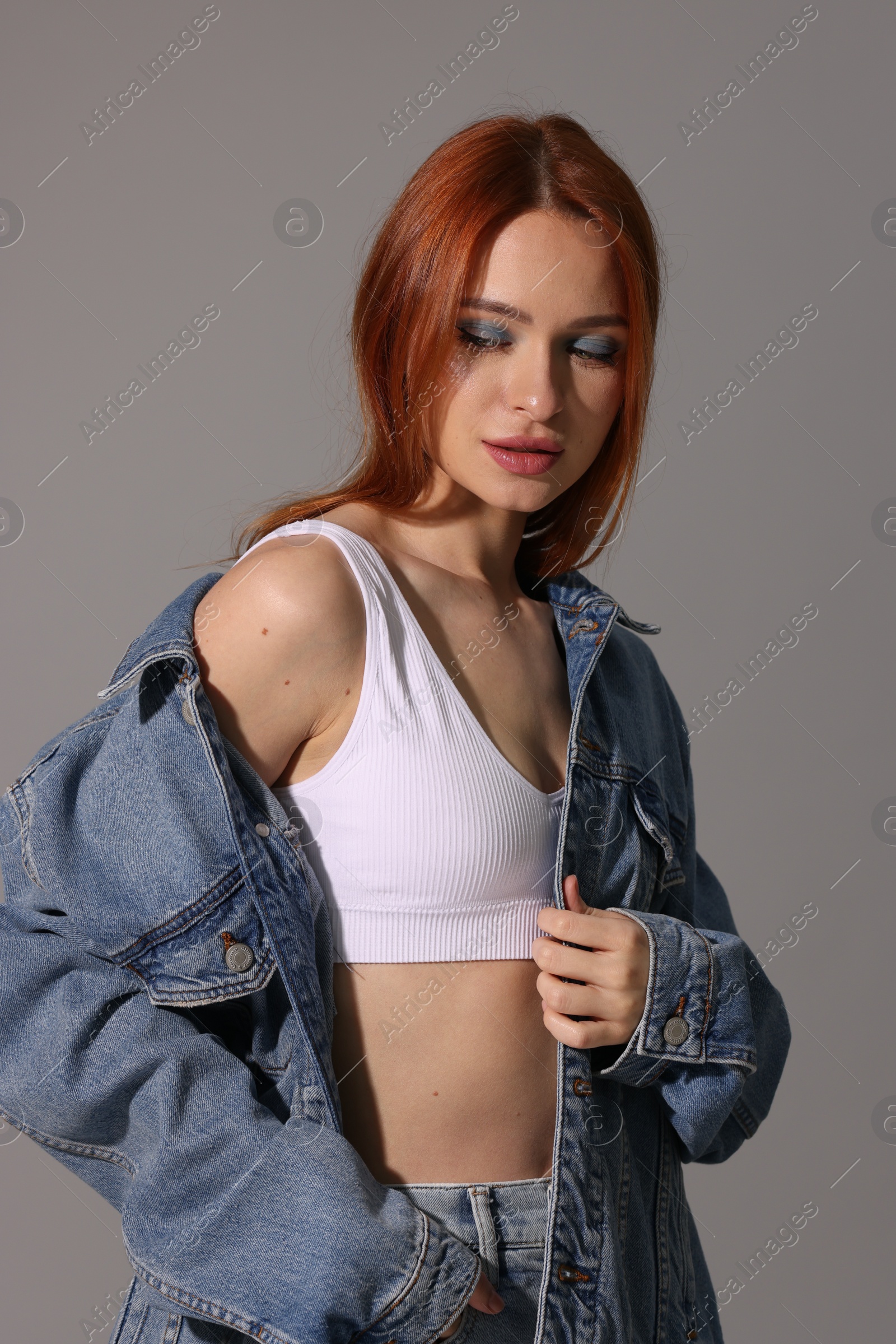 Photo of Beautiful young woman in denim jacket on gray background