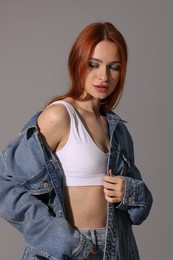 Photo of Beautiful young woman in denim jacket on gray background