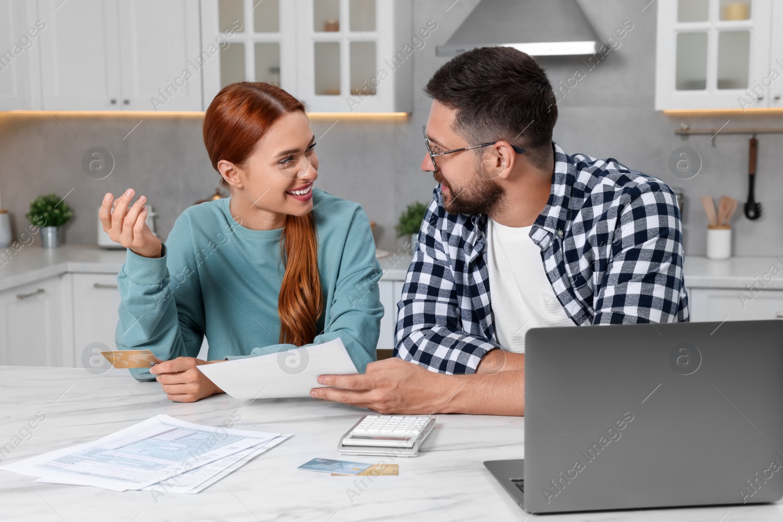 Photo of Couple with credit card using laptop for paying taxes online at home