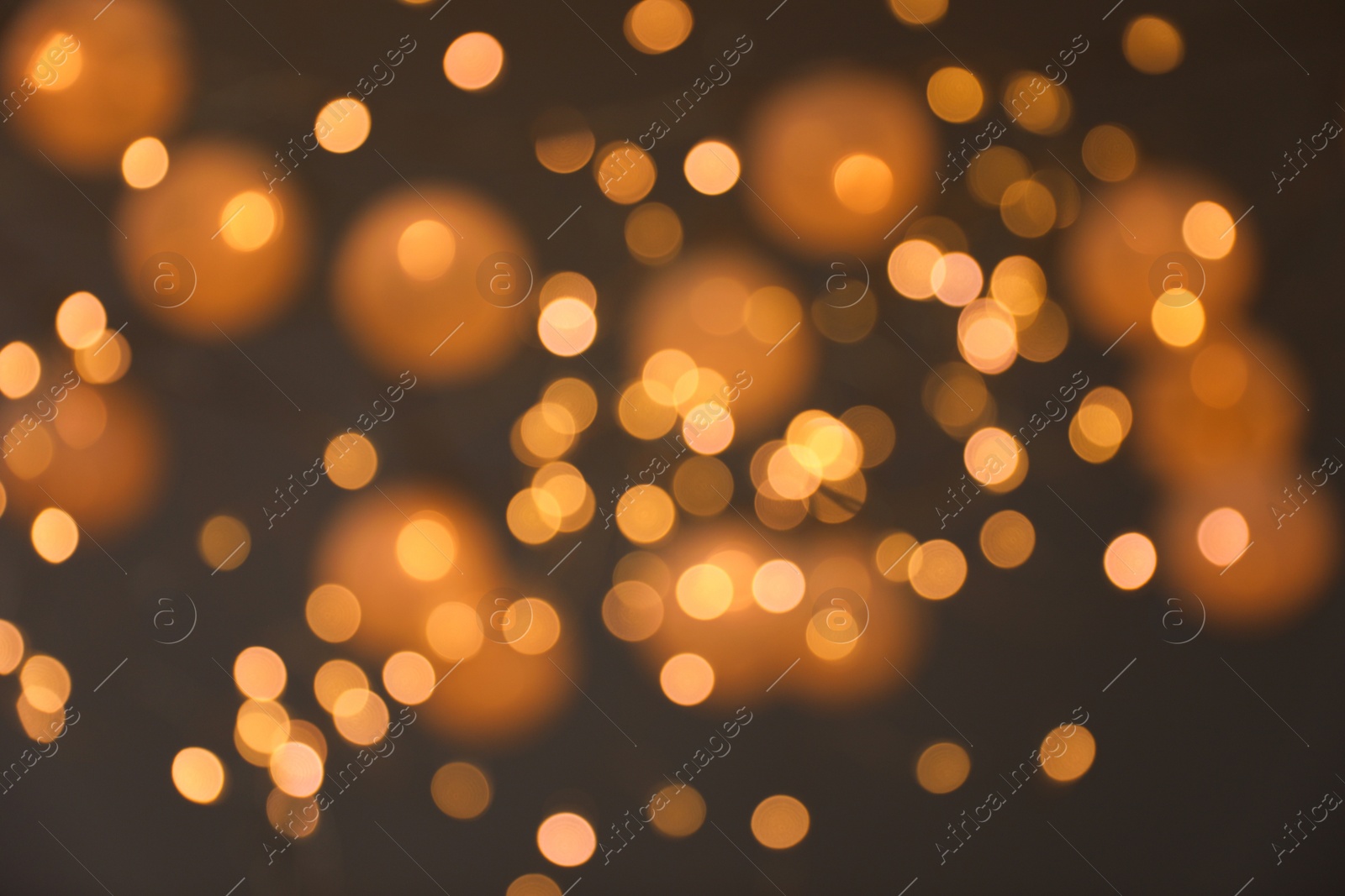 Photo of Blurred view of gold lights on dark background. Bokeh effect