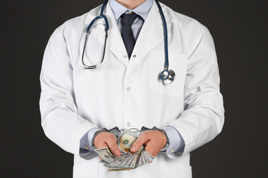 Doctor in handcuffs with bribe on black background, closeup. Corrupted medicine