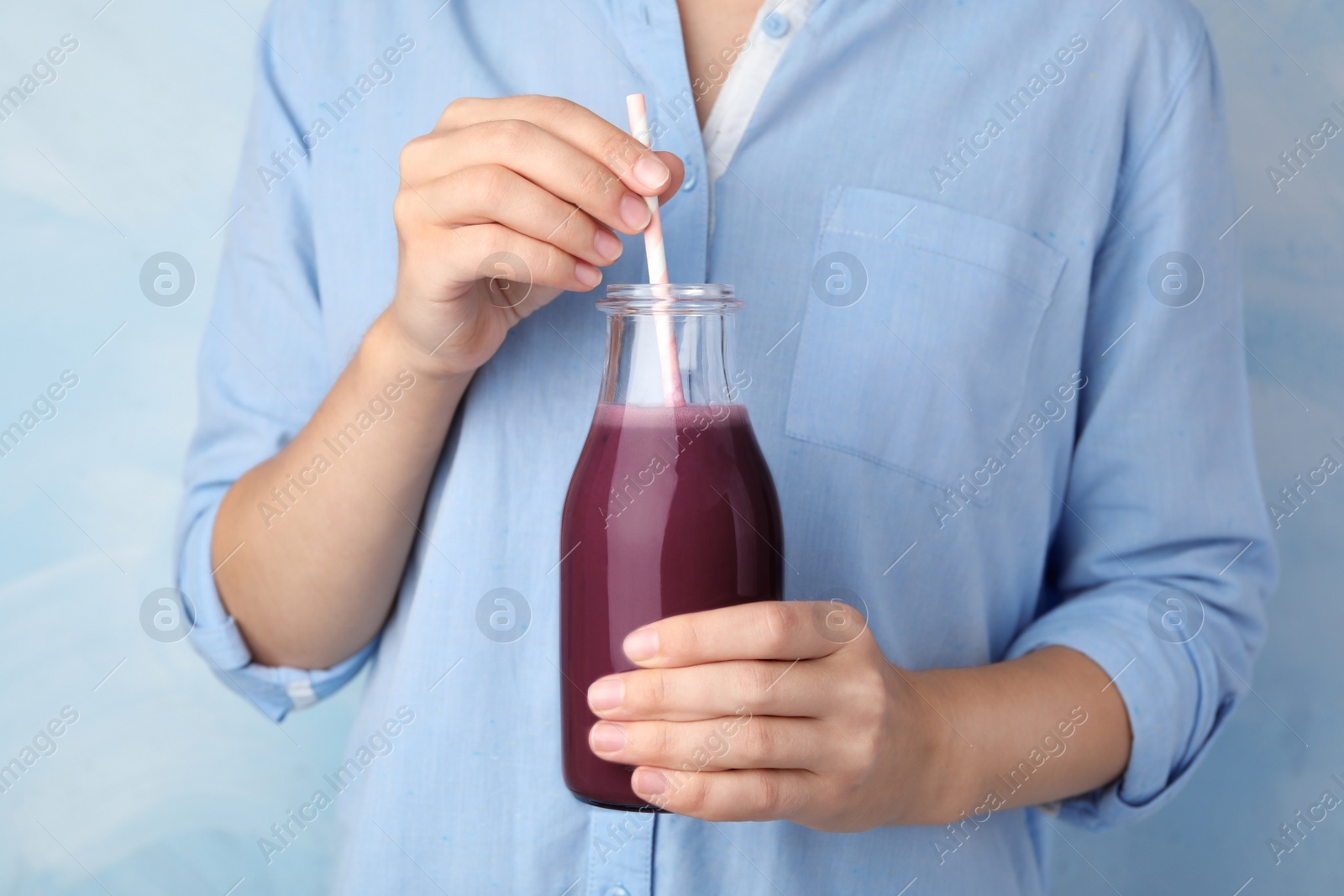 Photo of Woman with bottle of fresh acai drink and straw, closeup