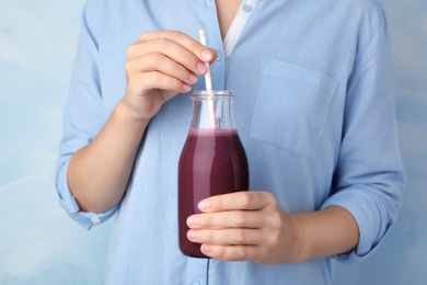 Photo of Woman with bottle of fresh acai drink and straw, closeup