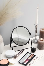 Photo of Dressing table with mirror, cosmetic products and burning candles in makeup room