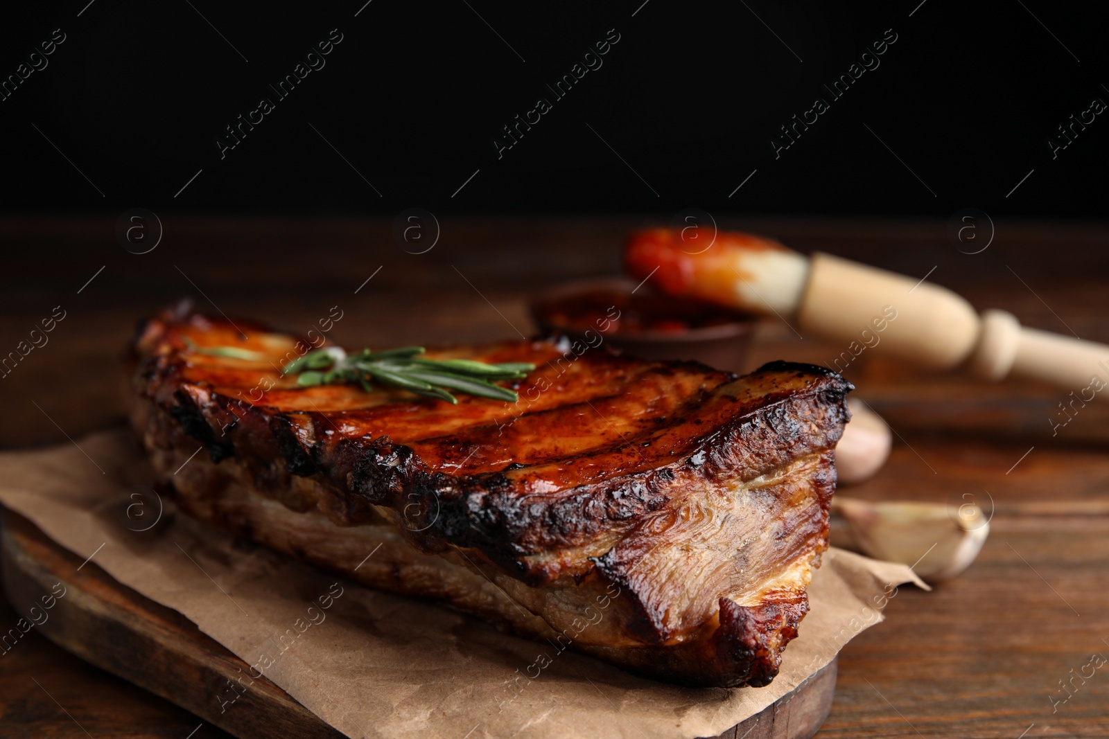 Photo of Tasty grilled ribs with rosemary on wooden table, closeup